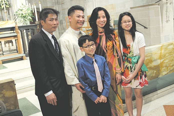 Father Richard Vu poses for a photographer off camera with (counterclockwise, from left) his brother Vy, his nine-year-old nephew Michael, his 13-year-old niece Anna and his sister-in-law Tien. Photo By Michael Alexander