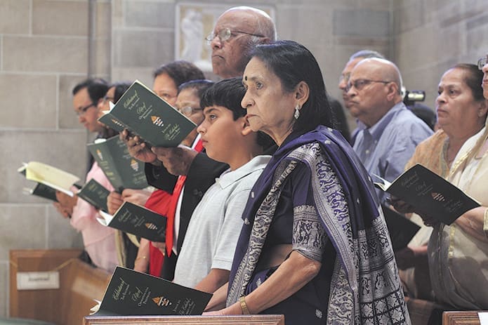 (Foreground to background, front row) During the procession of clergy to the altar, Rashmi Shroff, the mother of ordination candidate Gaurav, is joined in the pew with his 11-year-old nephew, Ahan, his oldest cousin, Dr. Soham Patel and a host of other relatives. While the mother and nephew live in India, Patel resides in Plasttsburgh, N.Y. Archdiocesan and visiting priests lay hands upon the seven ordination candidates during their June 8 ordination to the priesthood at the Cathedral of Christ the King, Atlanta. Photo By Michael Alexander