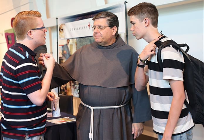 Order of Friars Minor Conventual Father Vincent Gluc talks with 21-year-old Jacob Ethridge, left, of St. Pius X Church, Conyers, and Ethridgeâs nephew, Tripp, of Grand Rapids, Minn. Father Gluc is the vocations director for the Our Lady of the Angels Province and he works out of Baltimore, Md. Photo By Michael Alexander