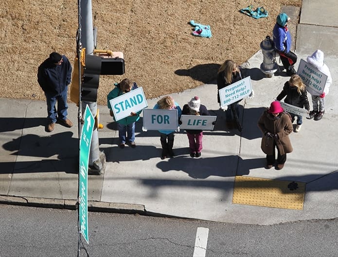 Standing at the intersection of Peachtree Road and Peachtree Way, Leslie Willis, her daughter Cami, and Maddie Cohen hold signs with Stand, For, and Life, respectively. Cami and Maddie attend St. John Bosco Academy, Suwanee. Photo By Michael Alexander