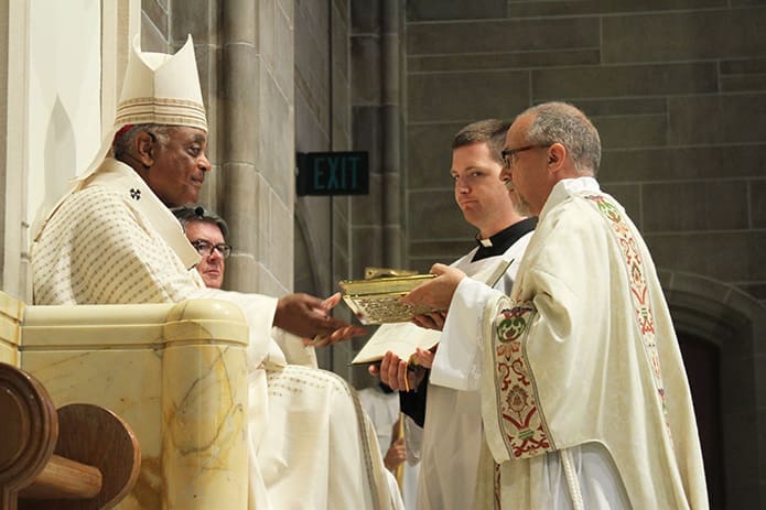 Archbishop Wilton D. Gregory, left, presents the Book of Gospels to newly ordained deacon, Rev. Mr. Mark Thomas. Photo By Michael Alexander