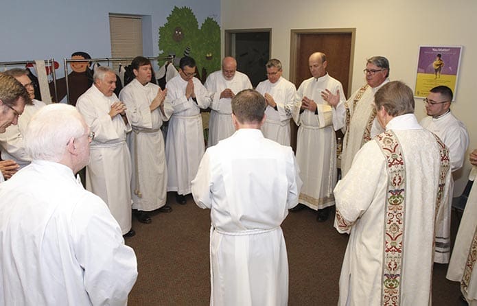 Prior to the diaconate ordination, the 13 candidates stand in silence as Deacon Dennis Dorner, third from right, director of the permanent diaconate, leads a prayer. Photo By Michael Alexander