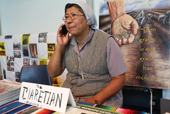 Claretian Missionary Sister Lili Tututi checks her voicemail messages as she sits at the vocation table for her order. Sister Tututi, who took her vows 15 years ago, resides and works in Miyo, Fla., which is part of the Diocese of St. Augustine. Photo By Michael Alexander