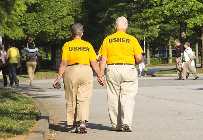 After serving the day as ushers, Elaine, left, and Edward Darr make their way back to parking lot at the conclusion of the 20th annual Eucharistic Congress at the Georgia International Convention Center, College Park. The Darrs, who will be married 59 years this coming August, attend St. Clare of Assisi Mission in Acworth. Photo By Michael Alexander
