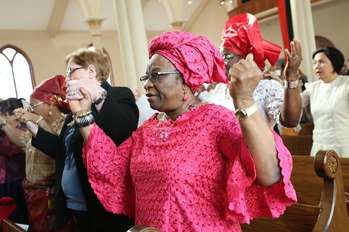 Carol Egbula joins with others in praying the Our Father. Egbula, a Nigerian by birth and a member of Sts. Peter and Paul Church, Decatur, was also part of a multicultural contingent that conducted the general intercessory prayers in their native language. Photo By Michael Alexander