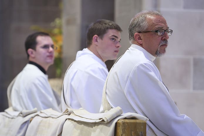 (L-r) Brian Bufford, Branson Hipp and Mark Thomas listen as Archbishop Wilton D. Gregory directs the words of his June 27 homily toward the five candidates to the priesthood. Photo By Michael Alexander