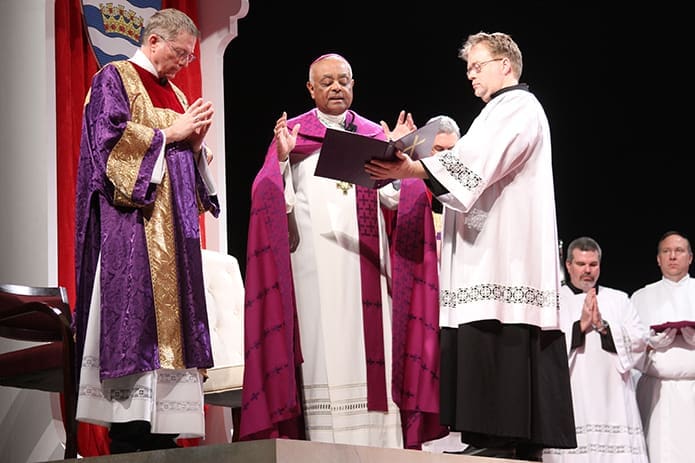 Archbishop Wilton D. Gregory conducts an opening prayer during the Feb. 22 Rite of Election as transitional deacon Michael Clendenning holds the book and permanent deacon Thomas Ryan of St. Catherine of Siena Church, Kennesaw, stands to the left. Photo By Michael Alexander