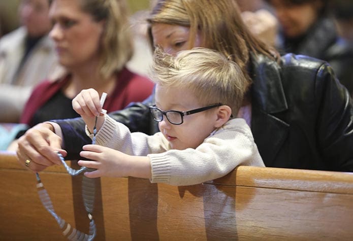 Katrina Lucisano of St. Benedict Church in Johns Creek helps her 3-year-old grandson from Charleston, S.C., follow the luminous mysteries of the rosary before the 26th annual Mass for the Unborn, Jan. 22. Photo By Michael Alexander
