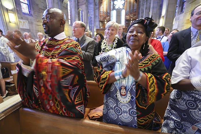 Harry Akoh, left, the brother of ordination candidate Valery Akoh, and their mother Hannah, join others in giving a standing ovation to all three ordination candidates as they are presented to the congregation. Photo By Michael Alexander