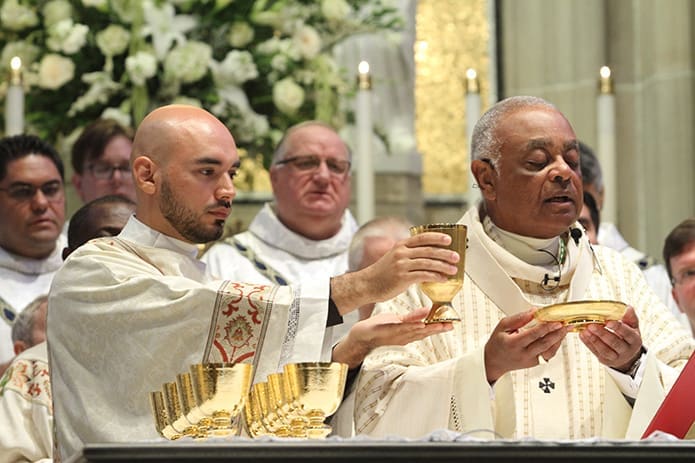 Rev. Mr. Carlos Cifuentes left, elevates the chalice and Archbishop Wilton D. Gregory elevates the paten during The Great Amen. Cifuentes will serve at Our Lady of Perpetual Help Church, Carrollton, during his assignment as deacon.  Photo By Michael Alexander