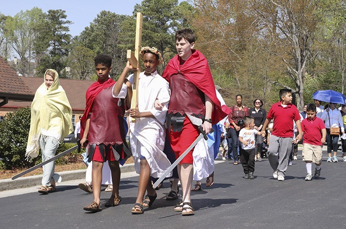 (L-r) A woman of Jerusalem (played by Kelly Humphrey) follows behind the Roman guard (played by Mason Benefield), Jesus (played by Darryl Cooper) and the Roman centurian (played by Ryan Law) as Jesus carries his cross just before he arrives at the sixth Station of the Cross (Veronica wipes the face of Jesus). Photo By Michael Alexander