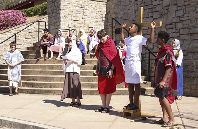 Just before the death of Jesus (played by Darryl Cooper), he looks up to heaven and cries out, “My God, my God, why have you forsaken me?” Women and Simon of Cyrene look on from a distance as Schaefer Hogan, foreground, fourth from right, reads a reflection for the 12th Station of the Cross (Jesus dies on the cross). Photo By Michael Alexander