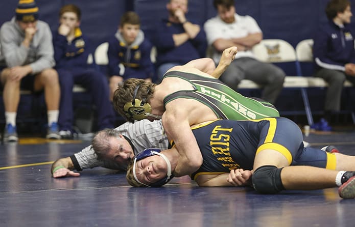 Blessed Trinity High School senior Daniel Fulcher, top right, and sophomore Jordan Secret of Marist School wrestle in the 152-pound division as referee Tom Dursee looks on. Fulcher was confirmed the winner after a first period pin. Photo By Michael Alexander