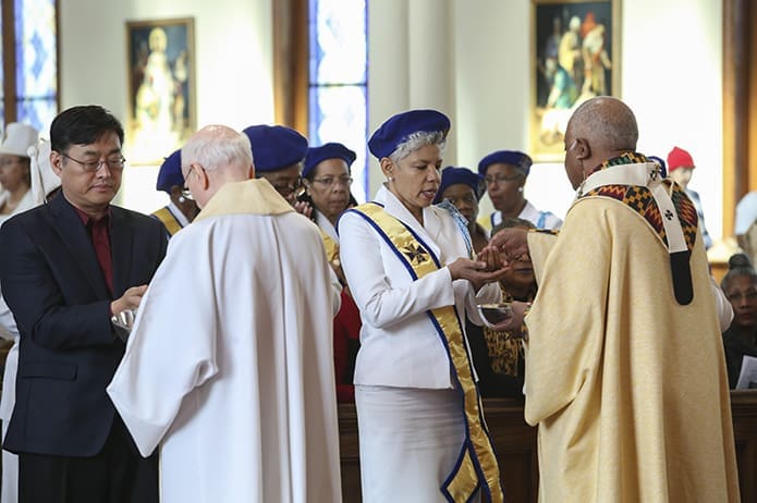 Passionist Father Jerome McKenna, second from left, and Archbishop Wilton D. Gregory, right, distribute holy Communion to the congregation during the Jan. 16 Martin Luther King Jr. Eucharistic Celebration at Atlanta’s Shrine of the Immaculate Conception. Photo By Michael Alexander