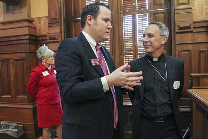 Atlanta House District 81 Representative Scott Holcomb, left, converses with Bishop Luis Zarama as the two stand inside the Georgia House of Representatives' chamber during the Feb. 21 Catholic Day at the Capitol. Representative Holcomb is a member of Immaculate Heart of Mary Church, Atlanta. Photo By Michael Alexander