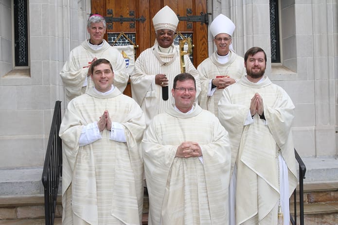 New priests Father Bryan Kuhr, front row, left, and Father Bradley Starr, front row, right, pose for a post-ordination photograph with vocations director, Father Timothy Hepburn, front row, center, and (back row, l-r) Bishop-designate Bernard E. (Ned) Shlesinger III, Archbishop Wilton D. Gregory and Auxiliary Bishop Luis R. Zarama. Photo By Michael Alexander