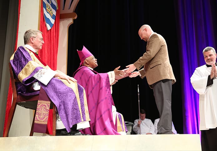 James Stone, director of catechesis for the RCIA program at St. Brendan the Navigator Church, Cumming, presents the Book of the Elect to Archbishop Wilton D. Gregory during the March 5 Rite of Election and the Call to Continuing Conversion. Photo By Michael Alexander