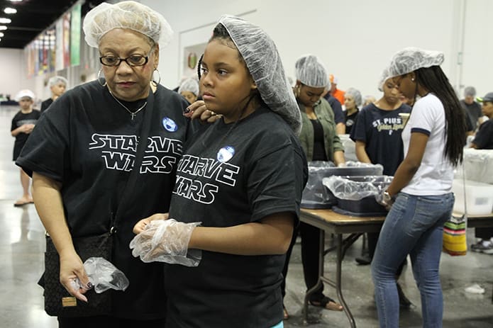 At the conclusion of Starve Wars’ first shift all the volunteers participated in a closing prayer. Here Chatta Douglas, left, prays with her 11-year-old granddaughter, Chas. Photo By Michael Alexander
