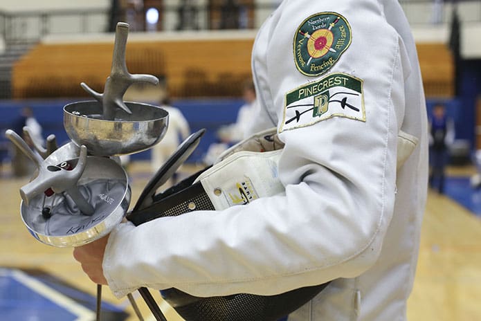 A Pinecrest Academy fencer holds his weapons and mask as he waits for his next bout during a Jan. 2016 tournament at Centennial High School in Roswell.