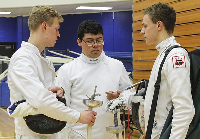 Alberto Figueredo, center, counts the number of bouts he had up to that point during a fencing tournament, December 2018, at Chattahoochee High School in Johns Creek. Standing with Figueredo are his teammates Andrew Flowers, left, and Matthew Crane, right. Photo By Michael Alexander