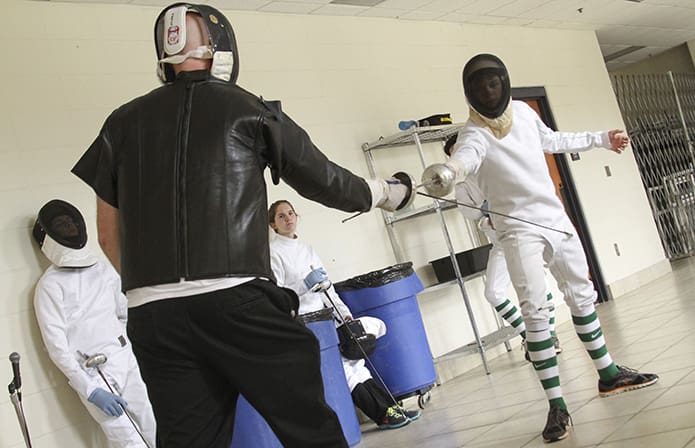 Head fencing coach Chad Morris, in black, explains the technique of extension versus jabbing to fencer Josiah Jones, right. At the time of this Sept. 2015 photo, the fencing team was holding practice in the school cafeteria. Photo By Michael Alexander