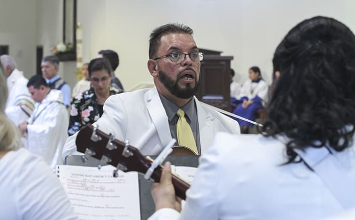 Victor Garcia, center, played guitar and directed the choir during the special service to dedicate the mission’s new worship space. Photo By Michael Alexander