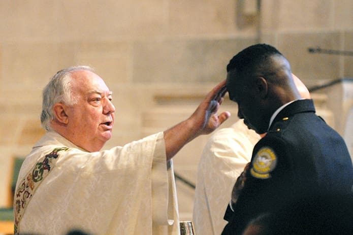 Msgr. Edward Dillon, pastor of Holy Spirit Church in Atlanta, blesses City of Atlanta Department of Corrections Lt. Michael Holmes during the Mass. A former chaplain of the Fulton County Police Department, Msgr. Dillon has also been chaplain of the Metro Atlanta Police Emerald Society since its inception in 1998. PHOTO BY LAURA MOON.