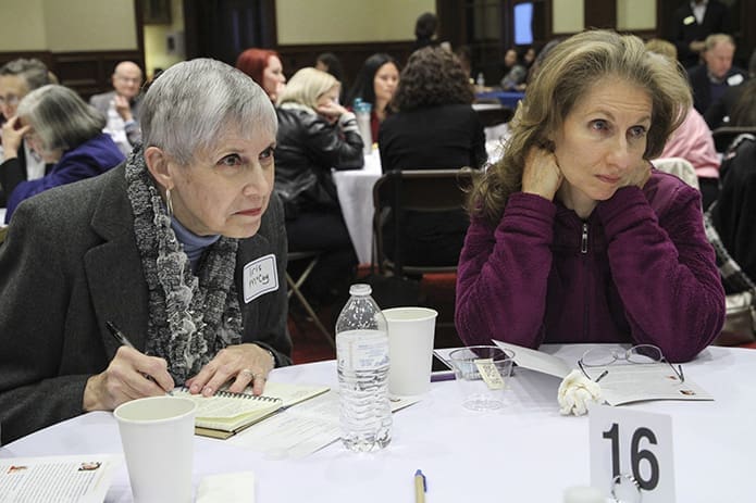 Iris McCoy of Holy Cross Church, Atlanta, left, takes notes and Susan Goldstein of Chabad of Cobb listens intently as someone shares at their table during a moment of discussion. Photo By Michael Alexander