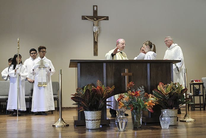 Bishop Joel M. Konzen, SM, fourth from right, conducts the prayer of dedication as altar server Maria Valdez, 16, holds the book. Looking on is Deacon Tom Ryan, far right, and Father Mark Starr, St. Clare of Assisi administrator. Photo By Michael Alexander