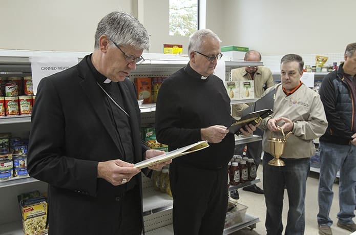 Bishop Bernard E. Shlesinger III, left, leads a prayer during the dedication of the St. Michael the Archangel Church food pantry. Standing next to the bishop is St. Michael the Archangel pastor Father Larry Niese. Photo By Michael Alexander