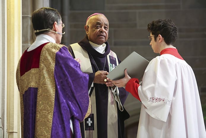 Joining Archbishop Wilton D. Gregory, center, on the altar are Deacon Tom Gotschall, left, chaplain for the Archdiocesan Catholic Committee on Scouting, and alter server Michael Marcinko, an Eagle Scout from the Cathedral of Christ the King’s Troop 74. Photo By Michael Alexander