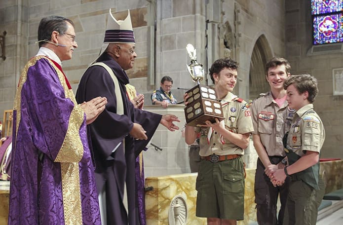 Archbishop Wilton D. Gregory, second from left, and Deacon Tom Gotschall, left, chaplain for the archdiocesan Catholic Committee on Scouting, present the Chaplain’s Cup to David Voll, Ryan Beason and Joseph Banks from Immaculate Heart of Mary Church’s Troop 550. Photo By Michael Alexander