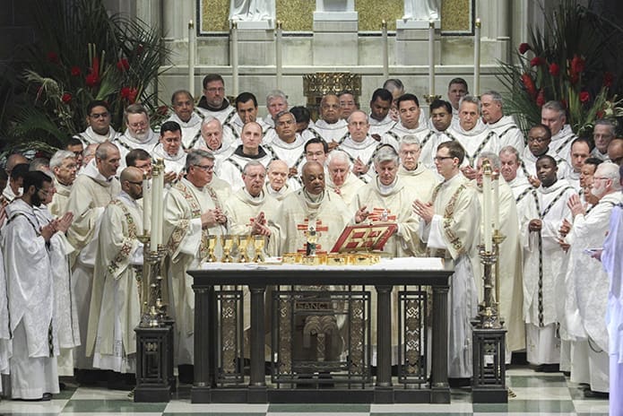 All the clergy in attendance for the 2018 Chrism Mass join Archbishop Wilton D. Gregory, center, on the altar during the Liturgy of the Eucharist. Photo By Michael Alexander