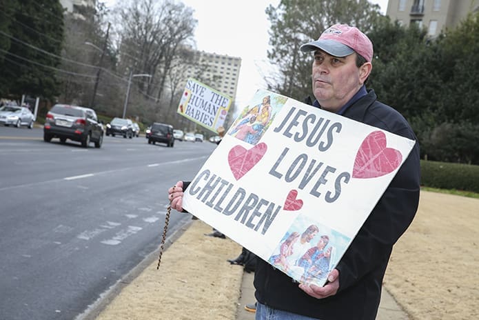 As motorists drive by, Brian Bimonte of St. Brigid Church, Johns Creek, holds his sign on the west side of Peachtree Road with others during Stand for Life Atlanta. The event, and the Mass for the Unborn preceding it, are sponsored by the Archdiocese of Atlanta’s Respect Life Ministry. Photo By Michael Alexander