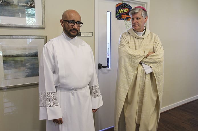 Just minutes before the June 16 rite of ordination to the priesthood, Rev. Mr. Carlos Ortega, left, waits in the Cathedral of Christ King’s ministry offices building with other clergy like Bishop Bernard E. Shlesinger III, right. Photo By Michael Alexander