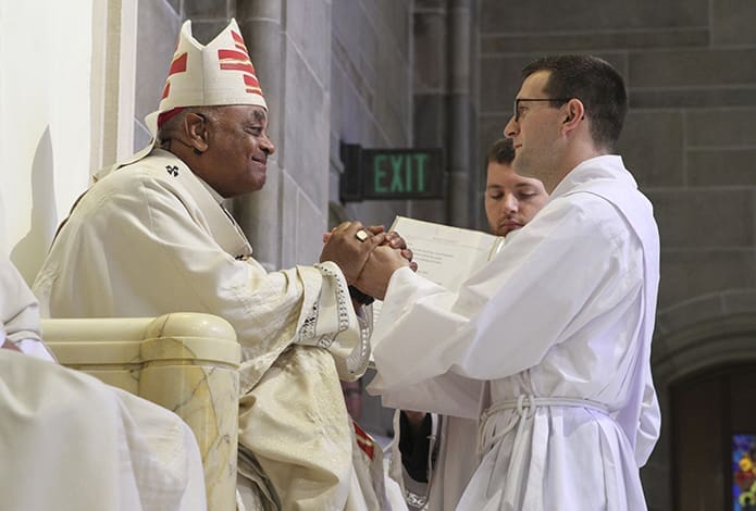 Rev. Mr. Michael Metz, right, pledges his obedience to Archbishop Wilton D. Gregory, left, and his successors. Photo By Michael Alexander