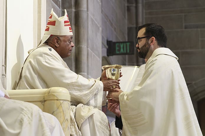 Archbishop Wilton D. Gregory, left, presents the chalice and paten, a sign of the new priest's office, to Father Jack Knight. The priest’s first assignment as parochial vicar will be at St. Benedict Church, Johns Creek. Photo By Michael Alexander. Photo By Michael Alexander