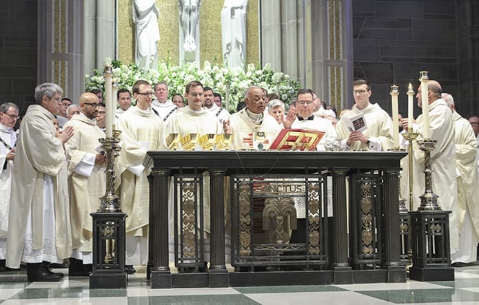 For the first time as ordained members of the priesthood, the five young men join Archbishop Wilton D. Gregory, center, around the altar for the Liturgy of the Eucharist. Photo By Michael Alexander