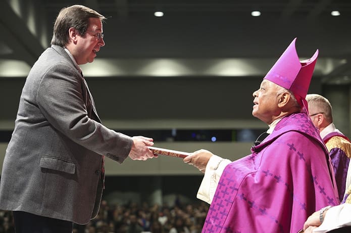 Vince DiMeo, left, a volunteer RCIA coordinator from St. Benedict Church, Johns Creek, presents the Book of the Elect to Archbishop Wilton D. Gregory during the Feb. 25 Rite of Election and the Call to Continuing Conversion. As a parish, St. Benedict Church has four catechumens and eight candidates. Photo By Michael Alexander