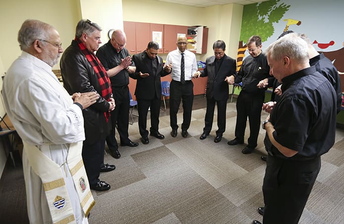 (Clockwise, from left) Deacon José Espinosa, associate co-director of formation, and Deacon Dennis Dorner, permanent diaconate director, pray with the eight permanent diaconate candidates before their Jan. 26 ordination. Photo By Michael Alexander