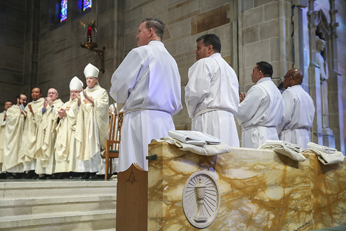 (Foreground, l-r) Timothy Tye, Randy Ortiz, Facundo Maldonado and Nicholas Goodly, four of the eight ordination candidates, can be seen as the clergy on the altar join the congregation in giving a standing ovation to all the candidates after their formal presentation during the Jan. 26 rite of ordination to the permanent diaconate. Photo By Michael Alexander
