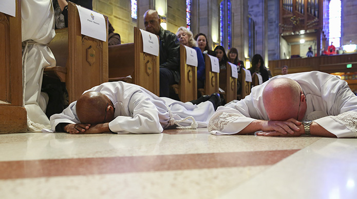 Nicholas Goodly, left, from St. John the Evangelist Church, Hapeville, and Timothy Dimond, right, from St. Benedict Church, Johns Creek, lie prostrate in the center aisle at the Cathedral of Christ the King, Atlanta. They were ordained to the permanent diaconate with six other candidates on Jan. 26. Photo By Michael Alexander