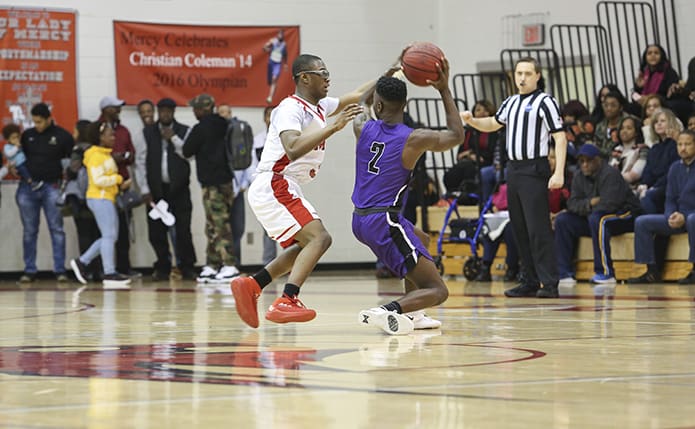 During the closing minutes of the game, Our Lady of Mercy High School junior guard John Wilson, left, plays some tight defense on Trinity Christian guard Tyler Whitfield (#2). Photo By Michael Alexander