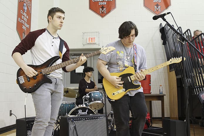 The Our Lady of Mercy High School pep band known as “Burnjar” consist of (clockwise, from left) senior Ryan Clemens on bass, sophomore Sebastian Ponce on drums and Jack Studdard on guitar. The band, which was formed in Jan. 2019, plays alternative rock and metal music during halftime and time-outs. Photo By Michael Alexander