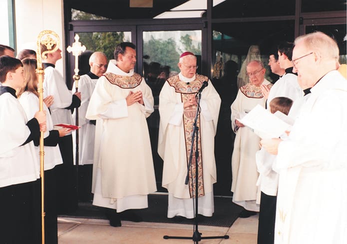 The late Archbishop John F. Donoghue, center, was the main celebrant during the Mass of Dedication nearly 21 years ago. This image shows them officially presenting the church to the archbishop before “unlocking of the doors.” Photo By Rick Taylor