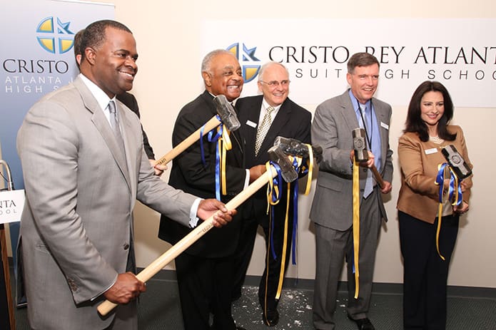 In September 2013 (l-r) Kasim Reed, Mayor of Atlanta, Archbishop Wilton D. Gregory, Bob Fitzgerald, Cristo Rey Atlanta board chair, Bill Garrett, president of Cristo Rey Atlanta, and Ileana Martinez, Cristo Rey Atlanta board member, pose for a photo holding sledgehammers. The groundbreaking at the former Archdiocese of Atlanta Chancery took the form of wall busting to symbolize the new renovations that would take place at the initial site of Cristo Rey Atlanta Jesuit High School. Photo By Michael Alexander