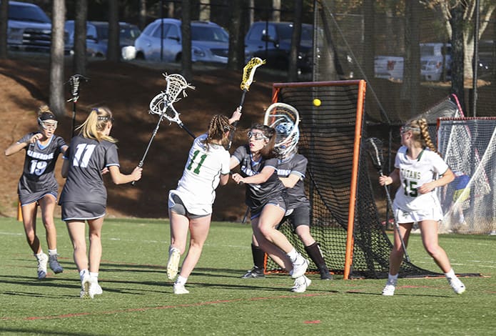 With an assist from Blessed Trinity midfielder Kaley Attaway, fellow midfielder Kelly Scott (#11) scores her third of four first-half goals, but Blessed Trinity suffered its first defeat of the season, a 17-13 loss to Milton’s Cambridge High School. Photo By Michael Alexander