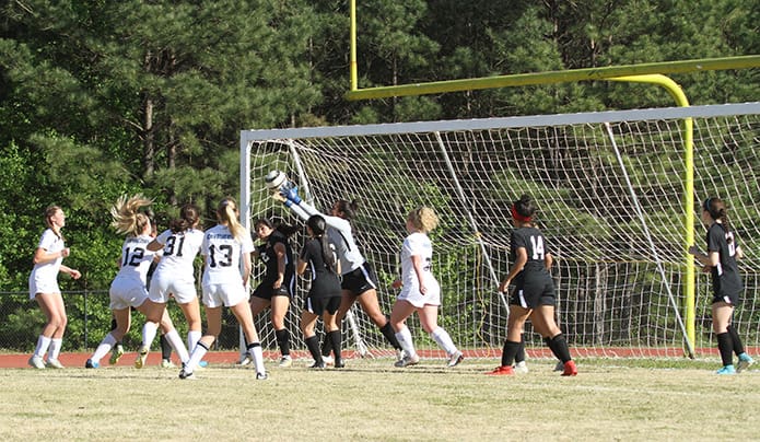 Our Lady of Mercy goalie Kaila Pouncy, fourth from right, reaches over her teammates to save a goal in the first half of the team's soccer match against Atlanta Classical Academy. Photo By Michael Alexander