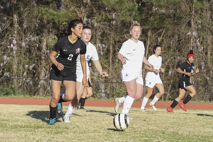 With her eyes looking up field, Our Lady of Mercy High School midfielder Abigail Barrantes (#2) advances the ball toward the Atlanta Classical Academy goal during the second half of the March 27 soccer match. Our Lady of Mercy would lose 5-0 on their home field. Photo By Michael Alexander