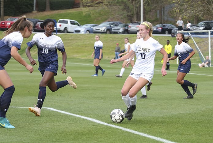 Marist School defensive back Eva Wirtz, left, and midfielder Annika Bryant (#18) give chase to St. Pius X forward Renee Lyles (#10), who scored one of the goals in St. Pius’ 2-0 victory over Marist. Photo By Michael Alexander